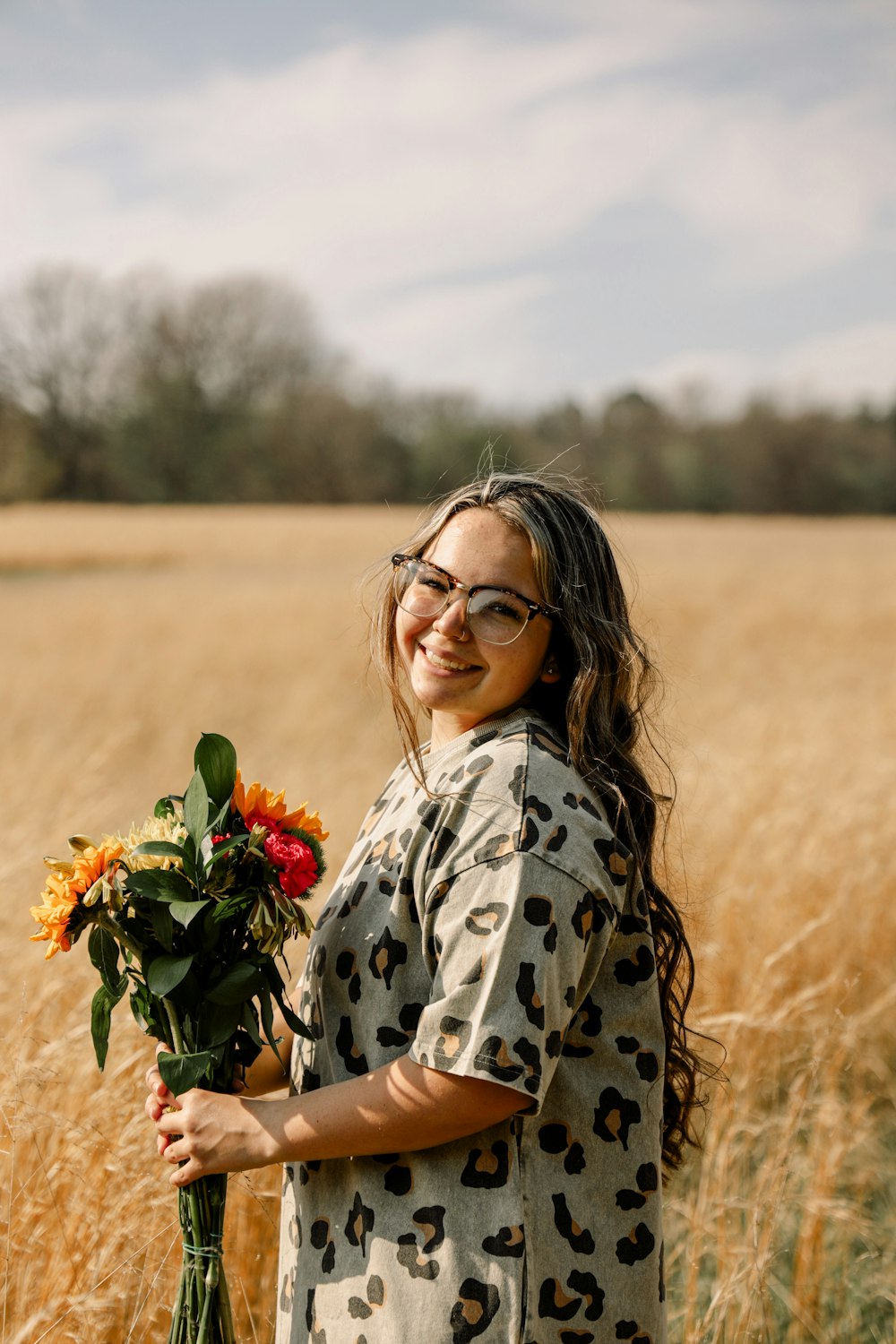 woman in white and black floral long sleeve shirt holding red flowers