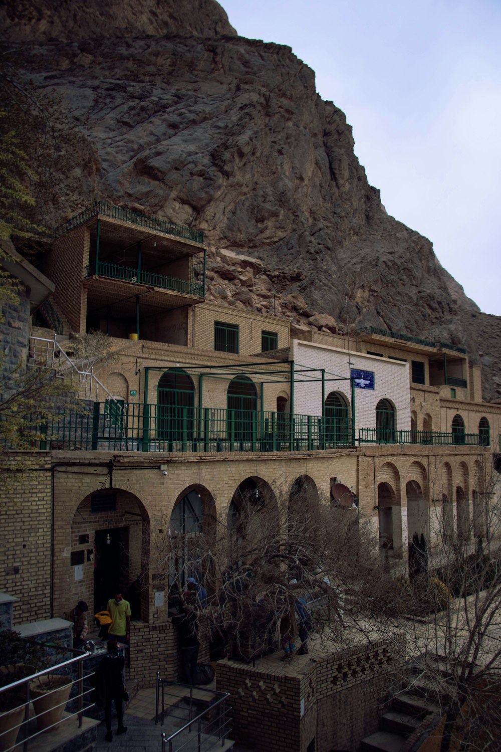 yellow and green concrete building near brown rocky mountain under white sky during daytime