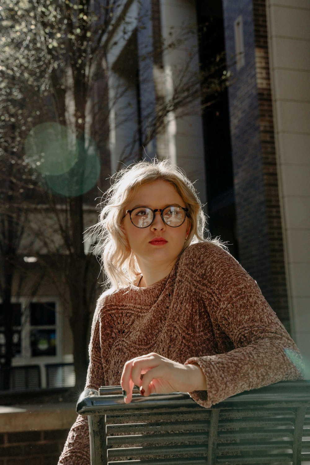 Femme en pull en tricot marron portant des lunettes à monture marron