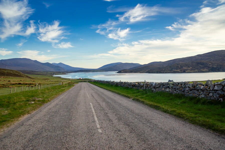 An empty road beside a loch under a blue sky