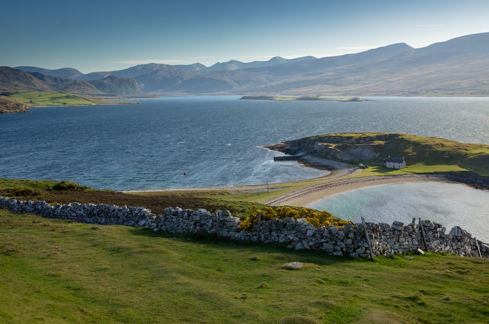 green grass field near body of water under blue sky during daytime