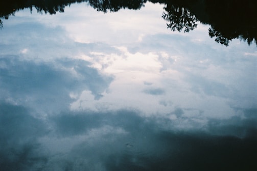 Reflections of trees and sky mirrored perfectly on still water.