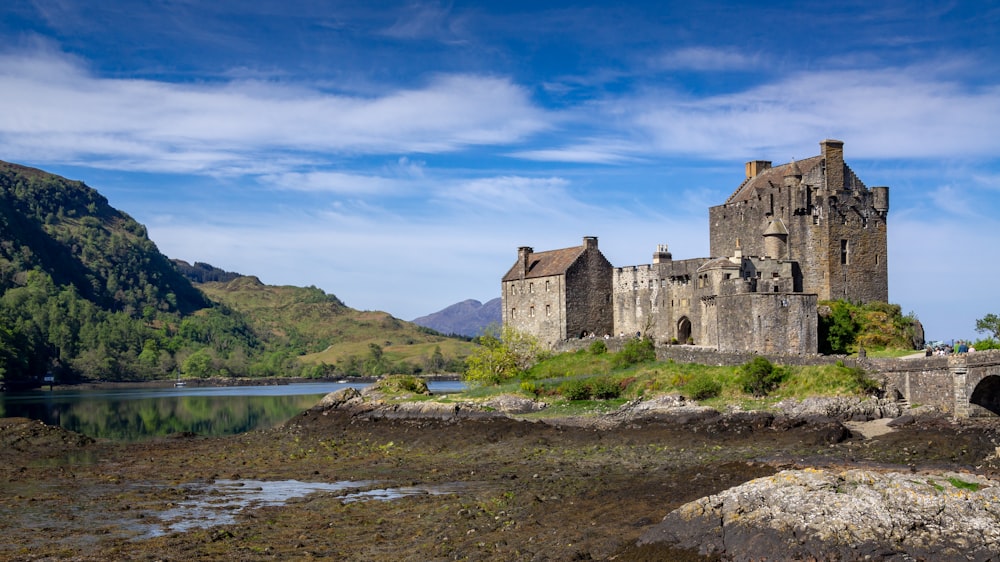 brown concrete castle near lake under blue sky during daytime