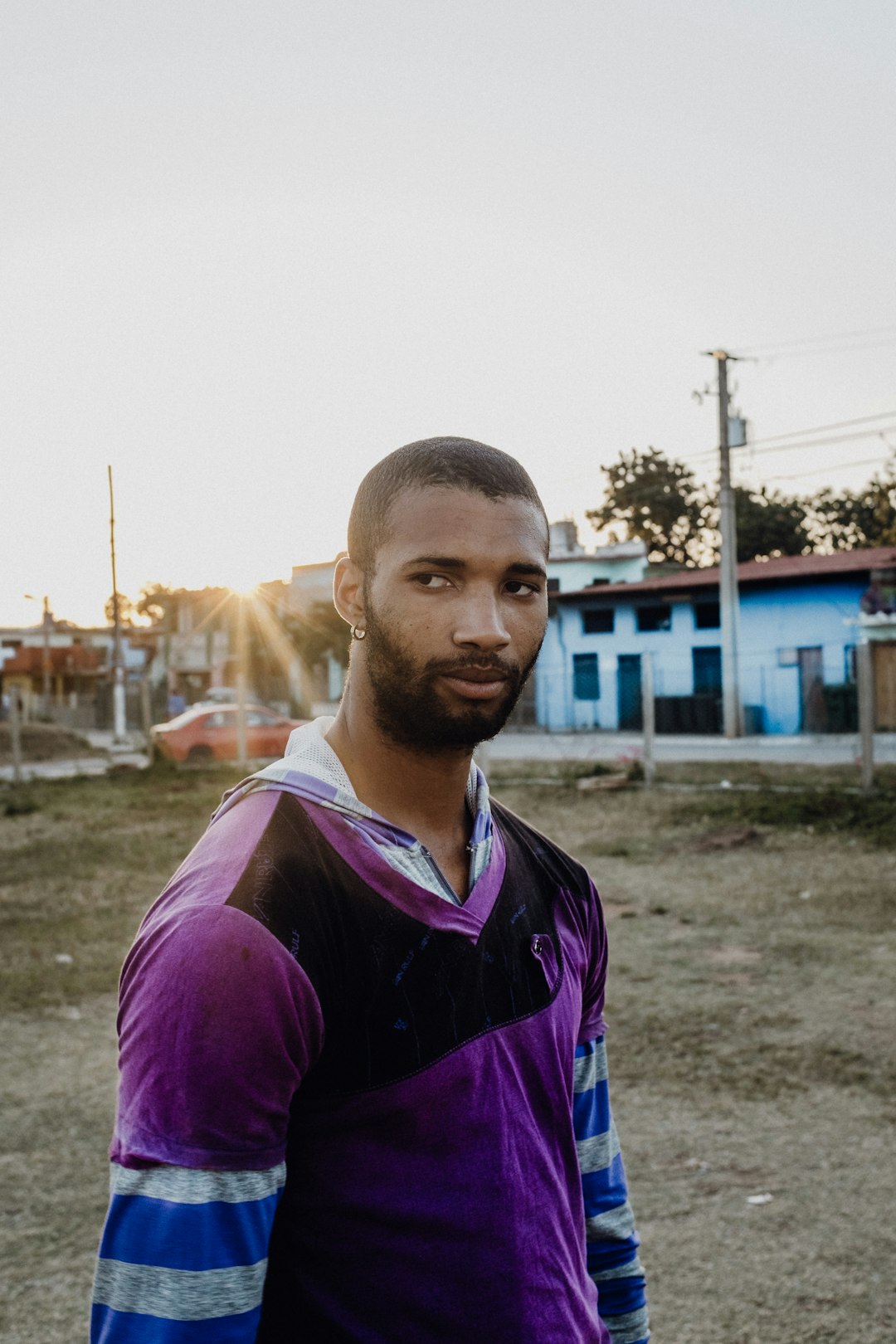 man in purple crew neck t-shirt standing on green grass field during daytime