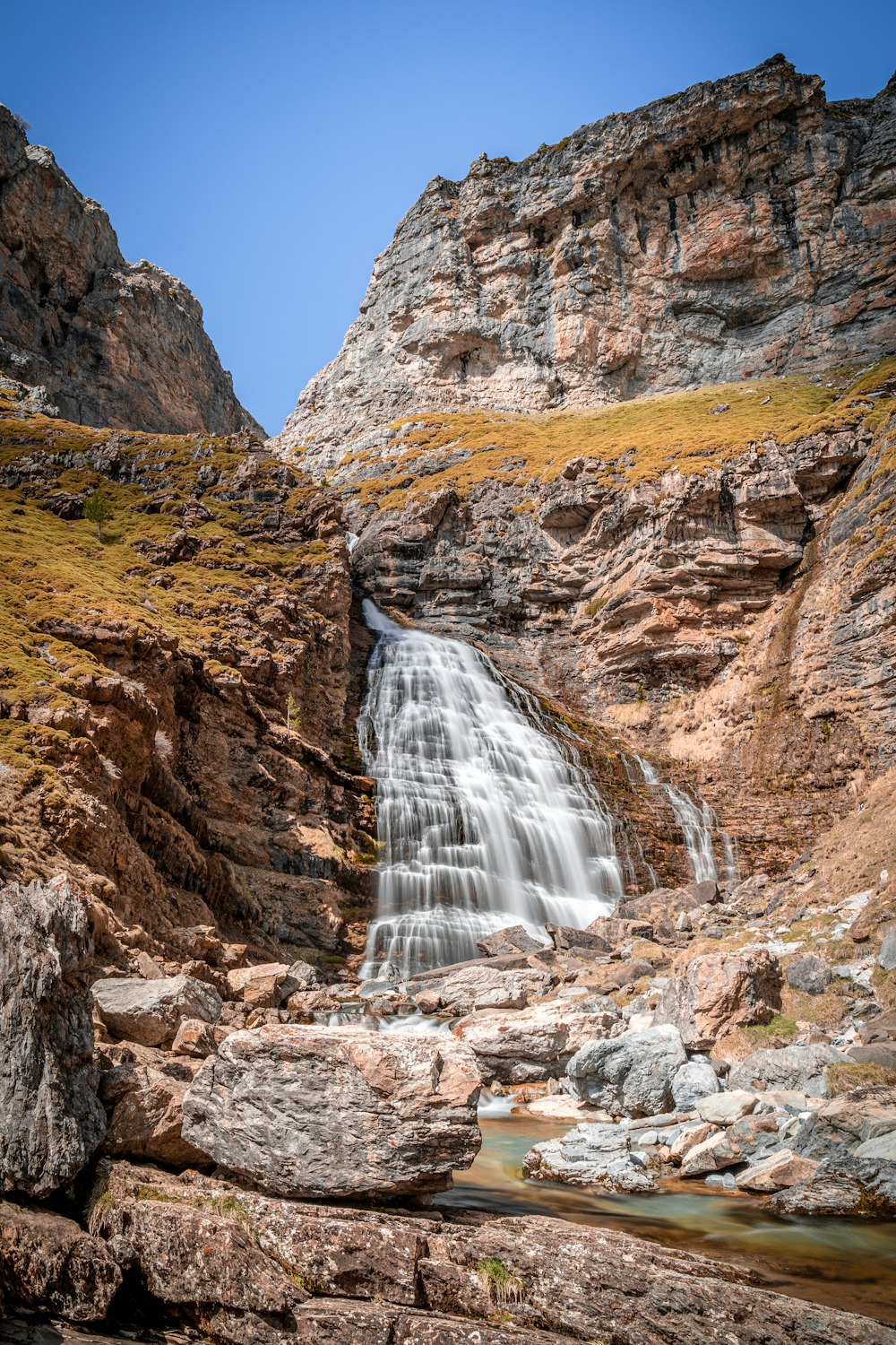 waterfalls in brown rocky mountain during daytime