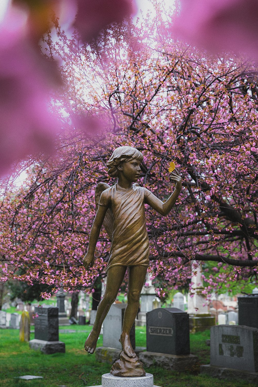 woman in green dress statue under pink leaf tree during daytime