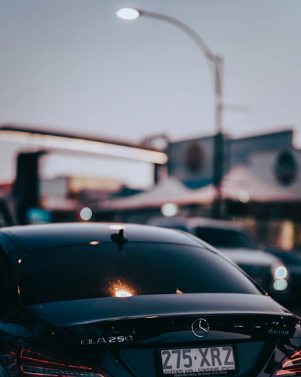 A sleek black Mercedes Classe E parked on a city street at dusk with soft golden lighting.