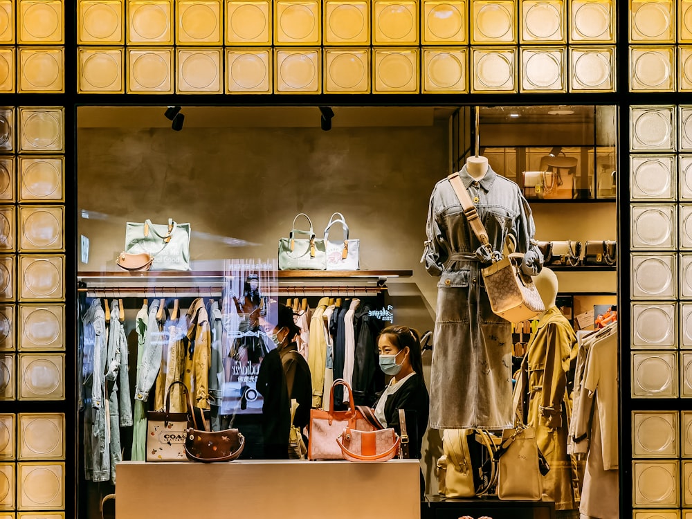 man in beige and brown uniform standing in front of clothes store