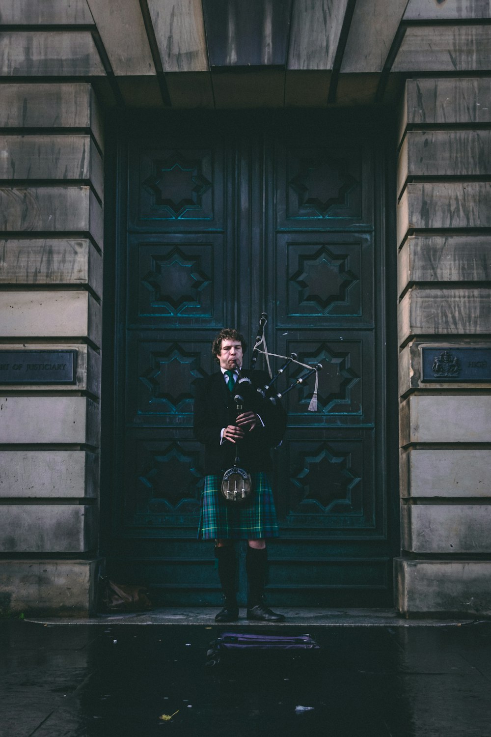 man in black jacket standing beside blue wooden door