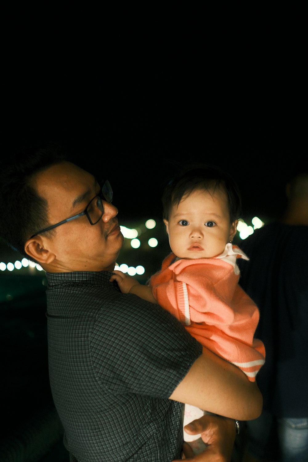 man in black shirt carrying baby in red hoodie