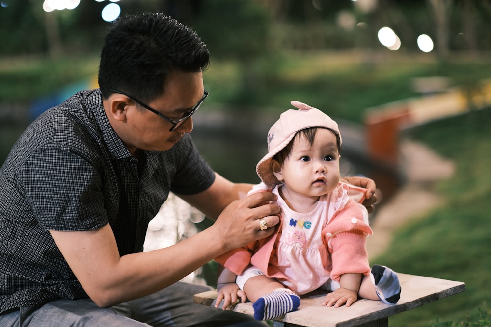 man in black crew neck t-shirt carrying baby in pink onesie