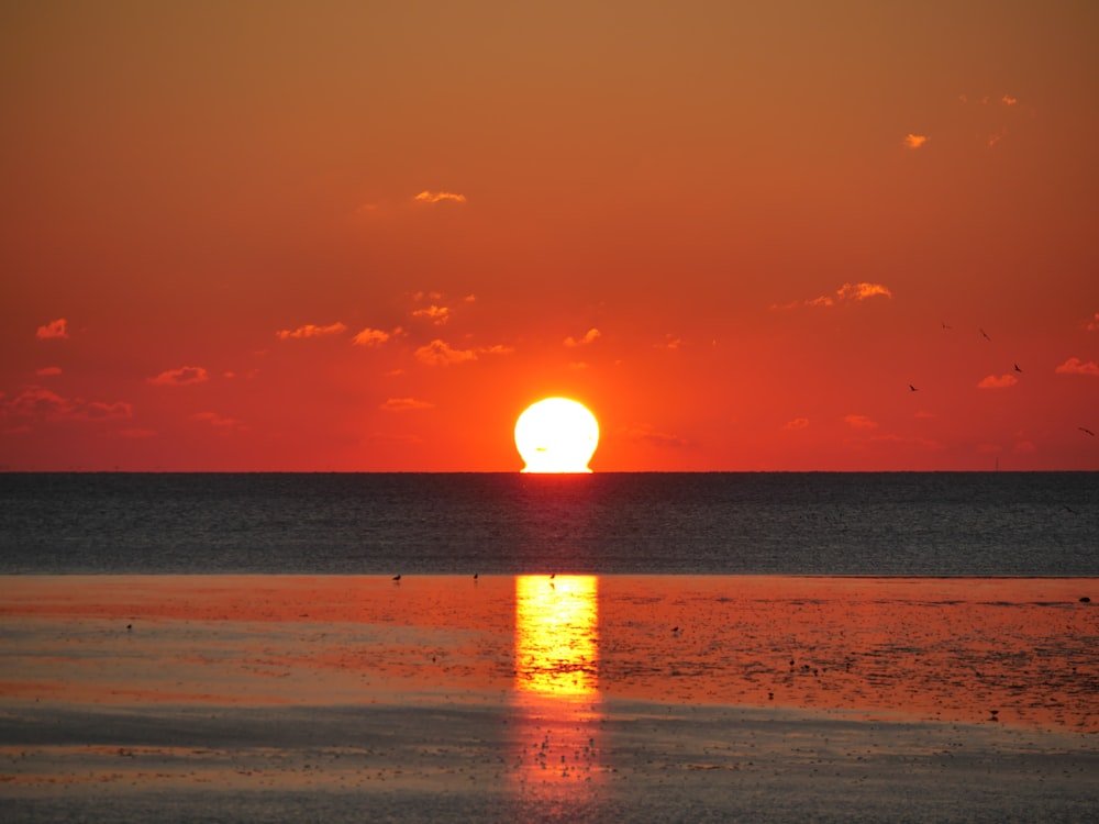 puesta de sol sobre el mar con gente caminando en la playa