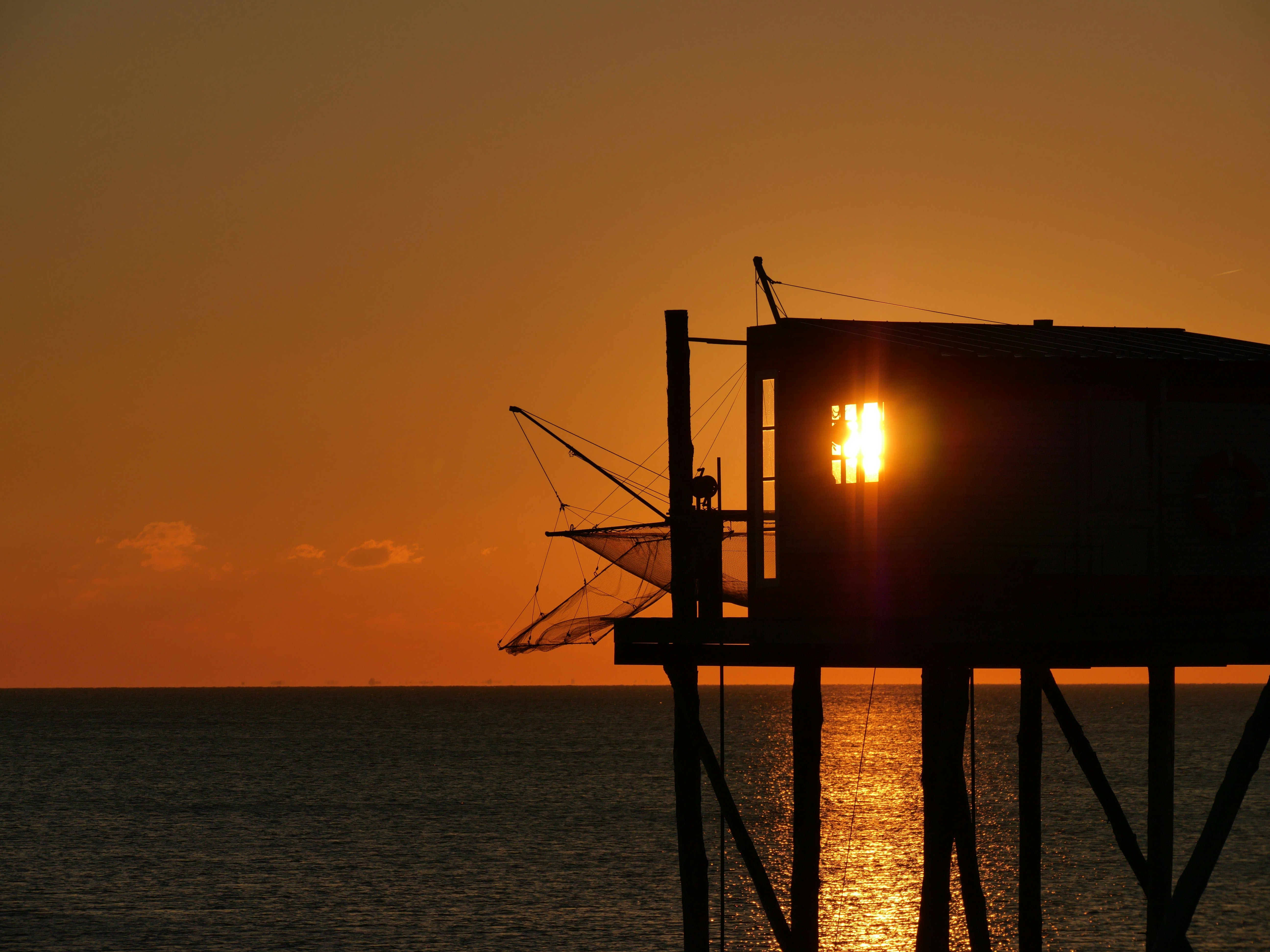 silhouette of a person standing on a wooden dock during sunset