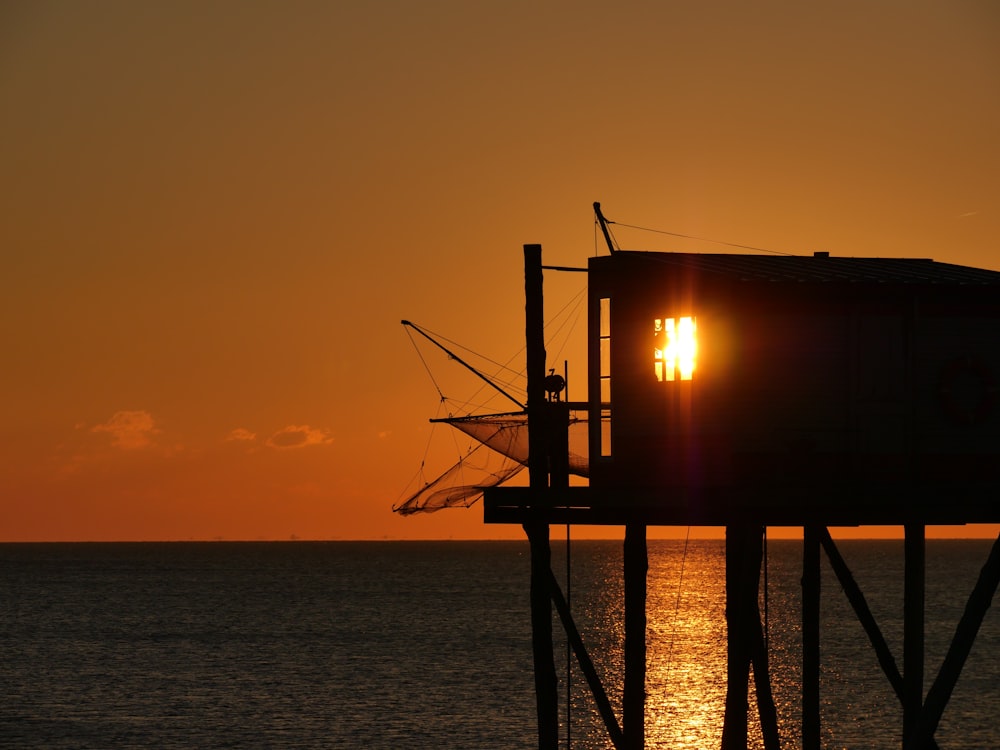 silhouette of a person standing on a wooden dock during sunset