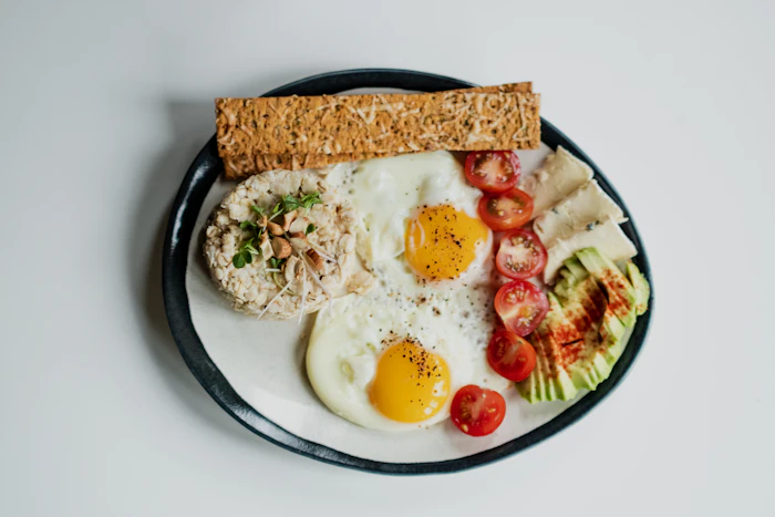 A colourful plated brunch dish with fried eggs and fresh vegetables