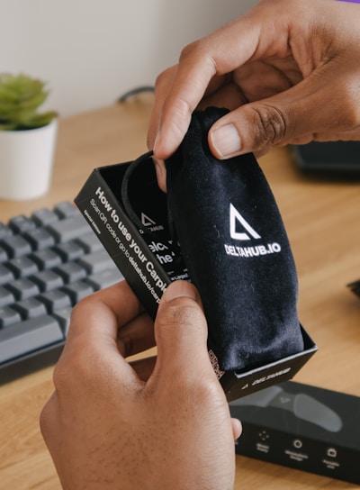 person holding black and white adidas pouch