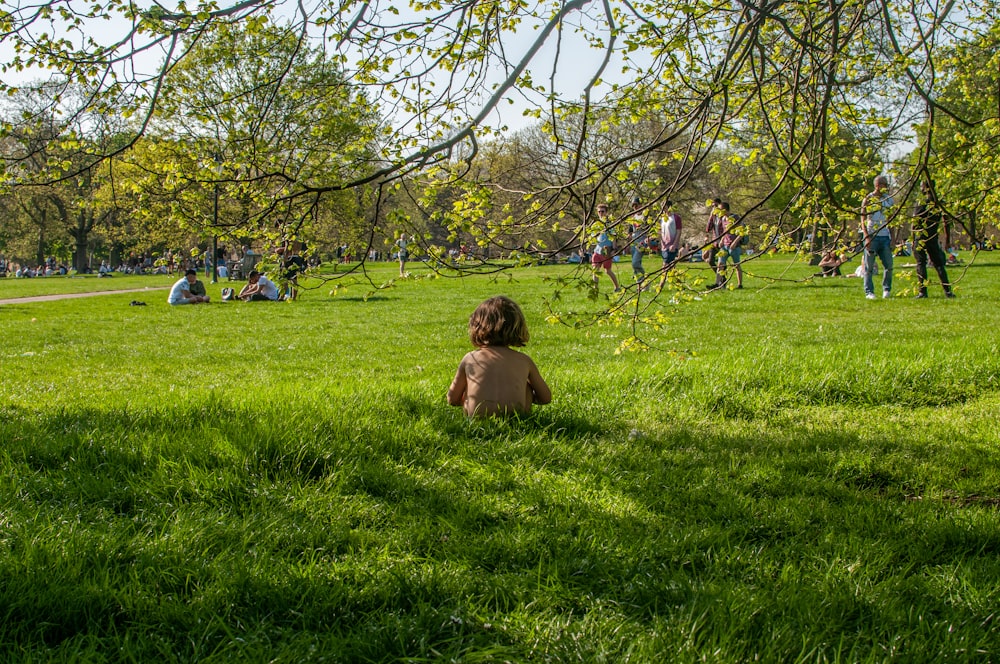 children sitting on green grass field during daytime
