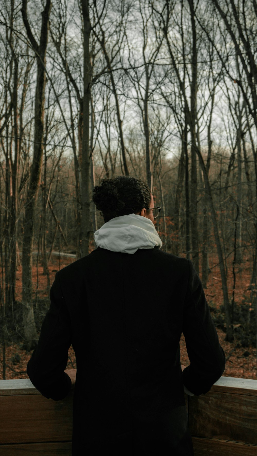 man in black jacket standing in the woods
