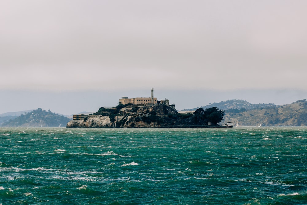 brown concrete building on top of rock formation on sea water during daytime