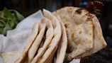 Steaming naan bread hot from the tandoor oven, showing soft texture.