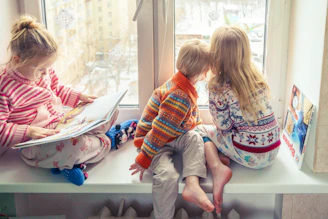 A warm nanny reading a storybook to two smiling children in a cozy living room.