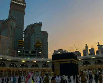 A serene view of pilgrims walking near the Kaaba during sunset.