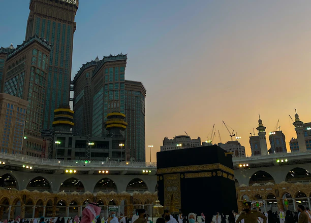 A serene view of pilgrims walking near the Kaaba during sunset.