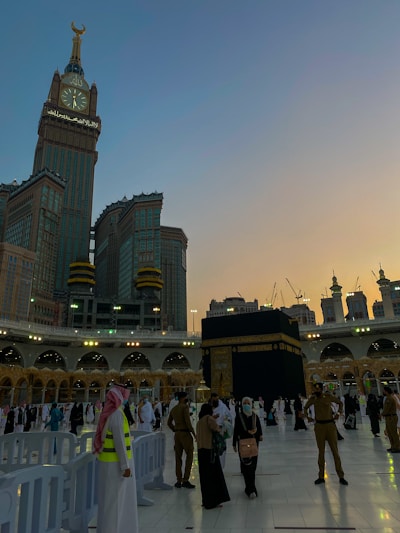 A serene sunrise over the Kaaba with pilgrims gathered in prayer, capturing the spiritual essence of the journey.