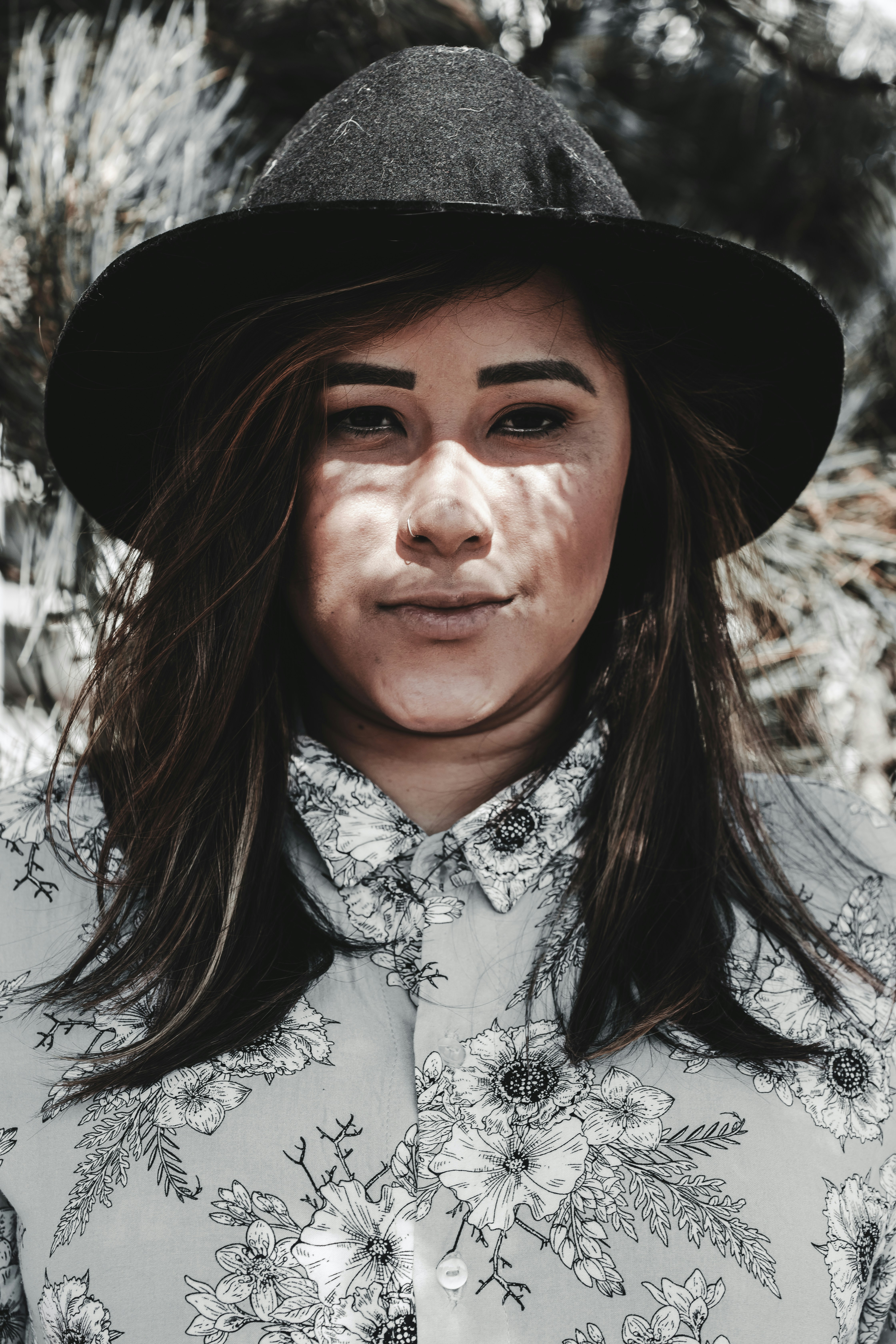 검은 모자를 쓴 흰색과 검은색 꽃무늬 단추 셔츠를 입은 남자