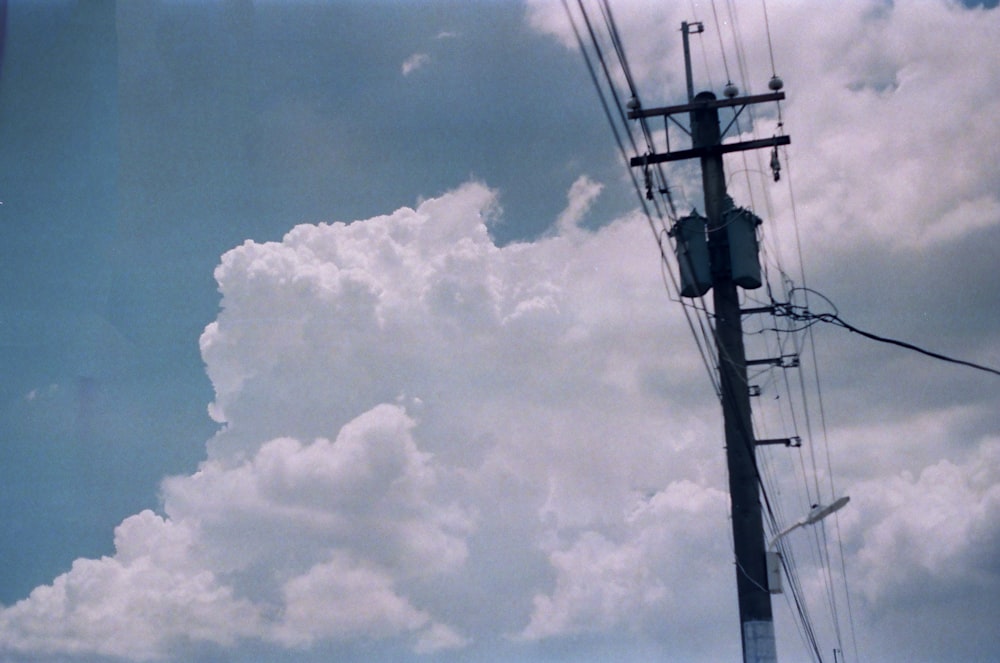 낮에는 흰 구름과 푸른 하늘 아래 검은 전기 기둥