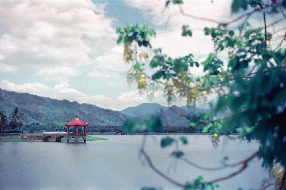 red wooden house on lake near green trees and mountain during daytime