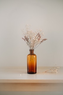 white dried flowers in amber glass bottle