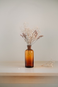 white dried flowers in amber glass bottle