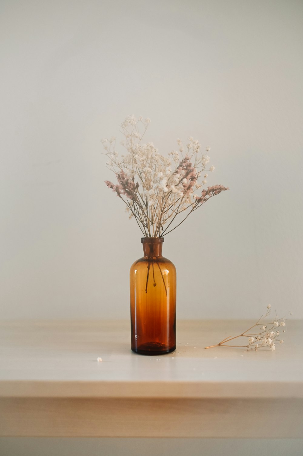 white flowers in brown glass bottle