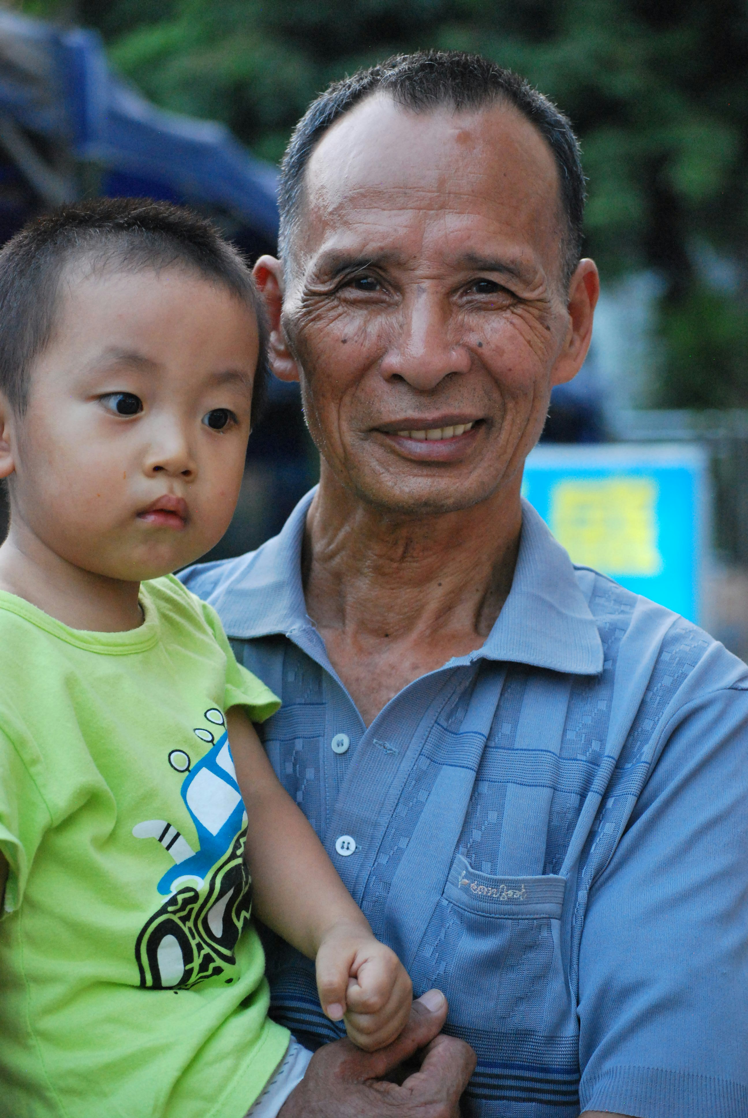 man in blue button up shirt carrying boy in green crew neck t-shirt