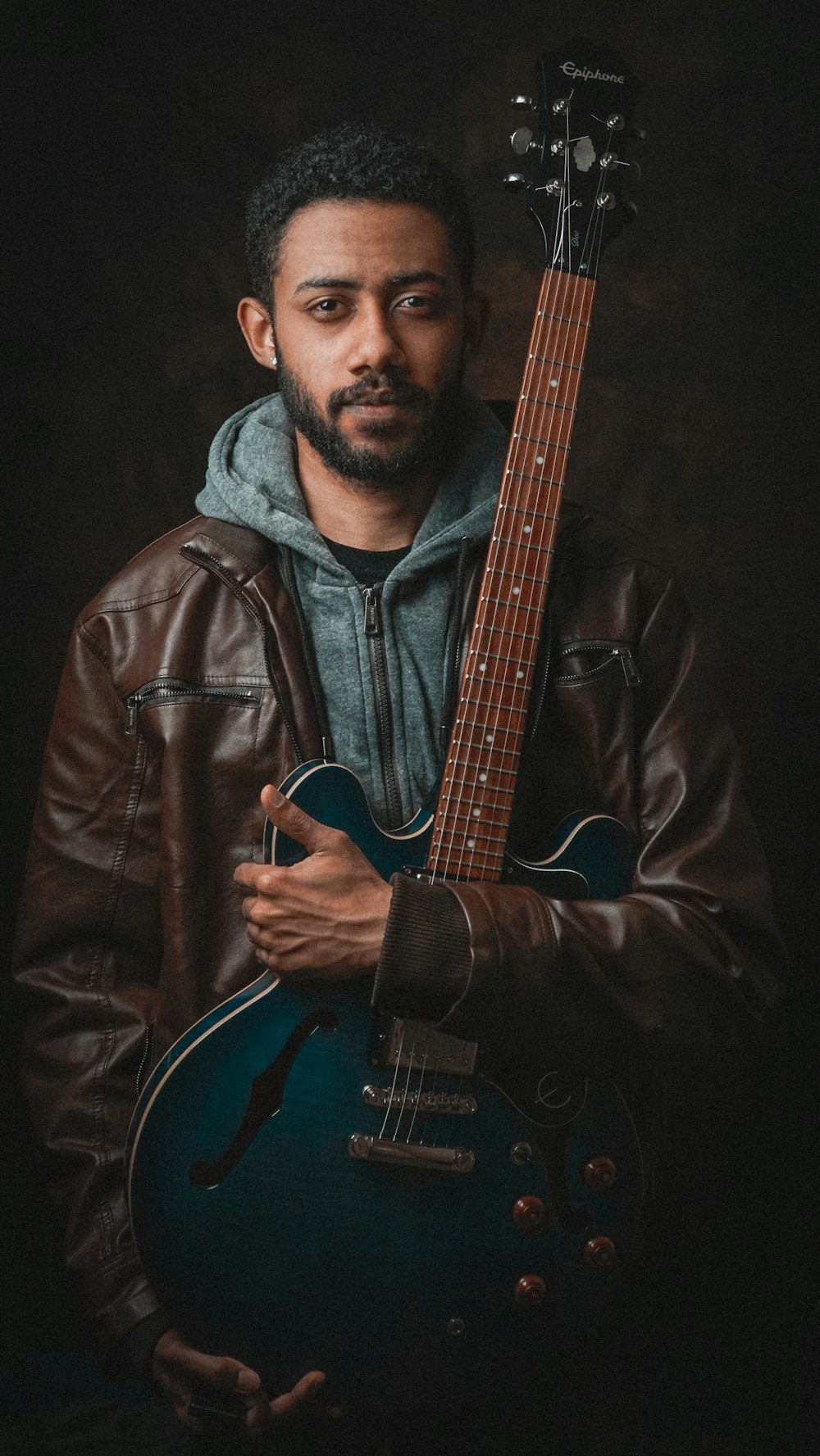 man in black leather jacket holding guitar