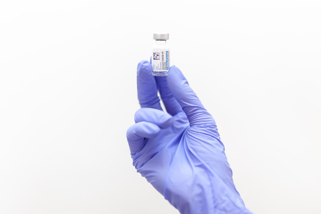 person holding black and white labeled bottle, Johnson & Johnson’s Janssen COVID-19 Vaccine