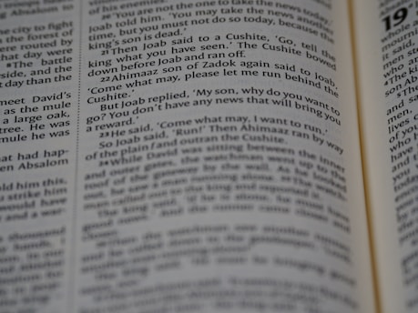 A close-up view of an opened book showing printed text in English. The focus is on the text in the central column, with surrounding text appearing slightly blurred due to the shallow depth of field.