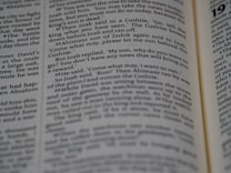 A close-up view of an opened book showing printed text in English. The focus is on the text in the central column, with surrounding text appearing slightly blurred due to the shallow depth of field.