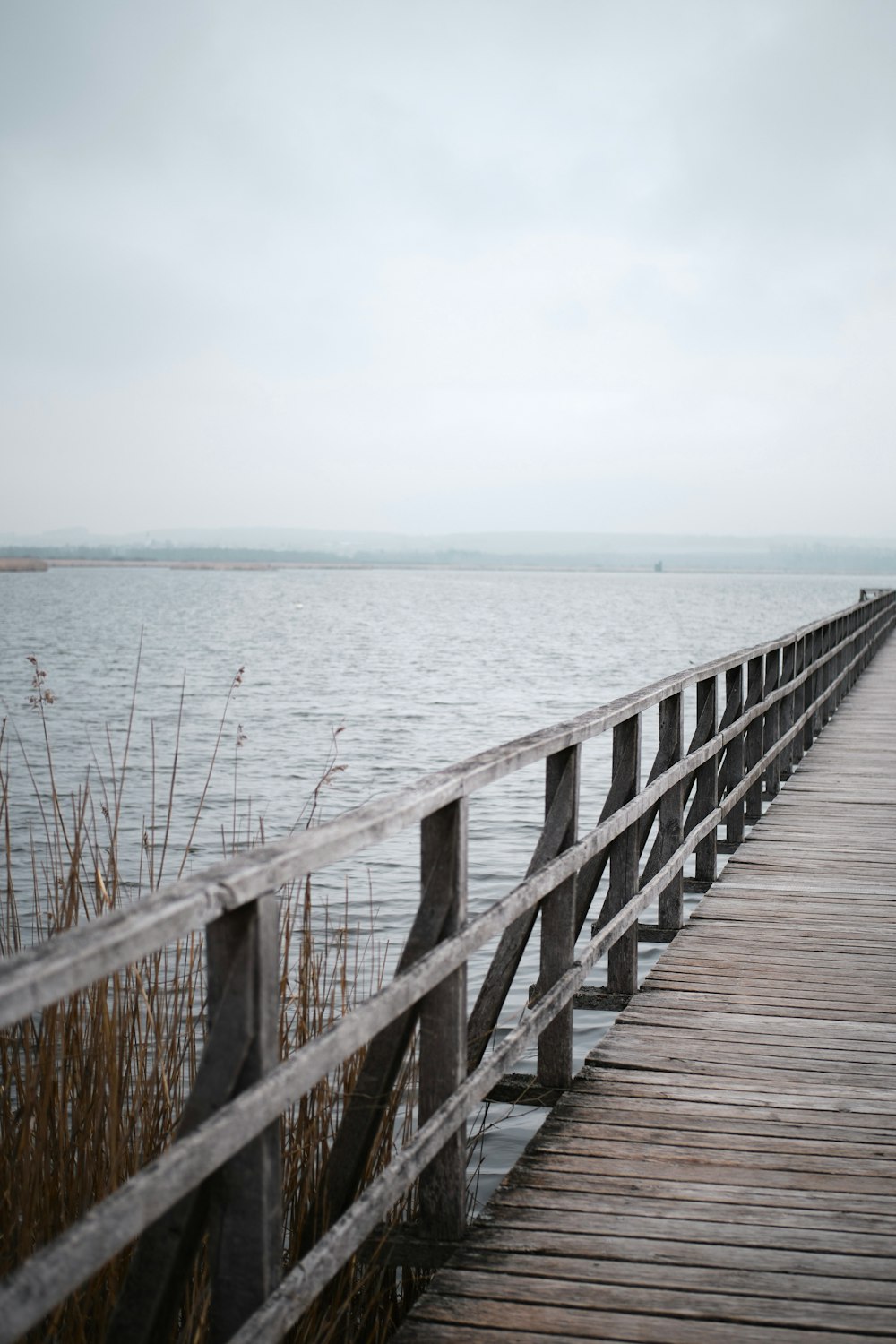 brown wooden dock on sea under white sky during daytime