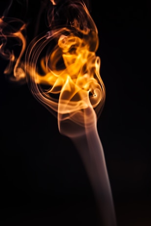 A slow-motion shot of amber vapor drifting upward from the saturix smoker, illuminated by pulsing gold reflections.