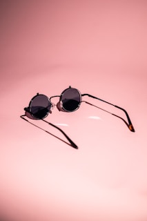 Stylish sunglasses resting on a white surface with soft shadows and smooth reflections.