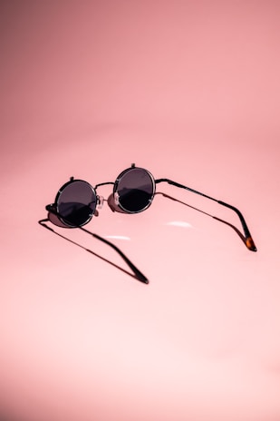 Stylish sunglasses resting on a white surface with soft shadows and smooth reflections.