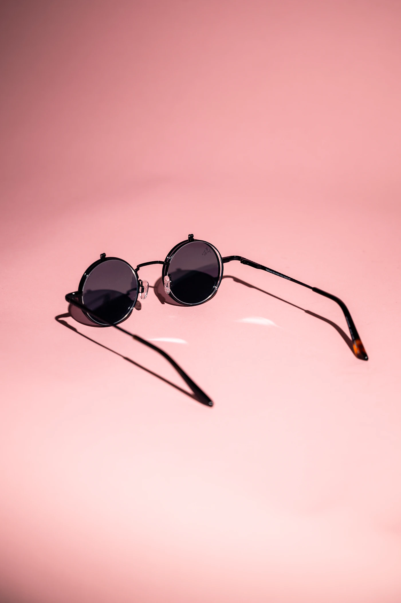 Angular sunglasses photographed against a soft pink background