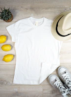 Flat lay of natural-toned caps and t-shirts with custom prints arranged on a light beige surface