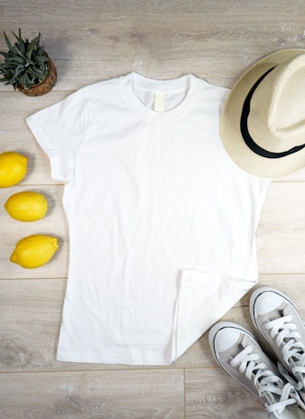 A flat lay of various clothing items including a t-shirt and cap on a wooden surface.