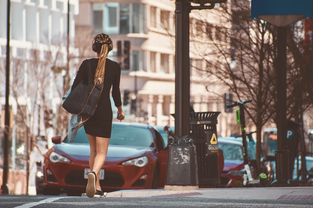 woman in black long sleeve shirt and black skirt standing beside red car during daytime