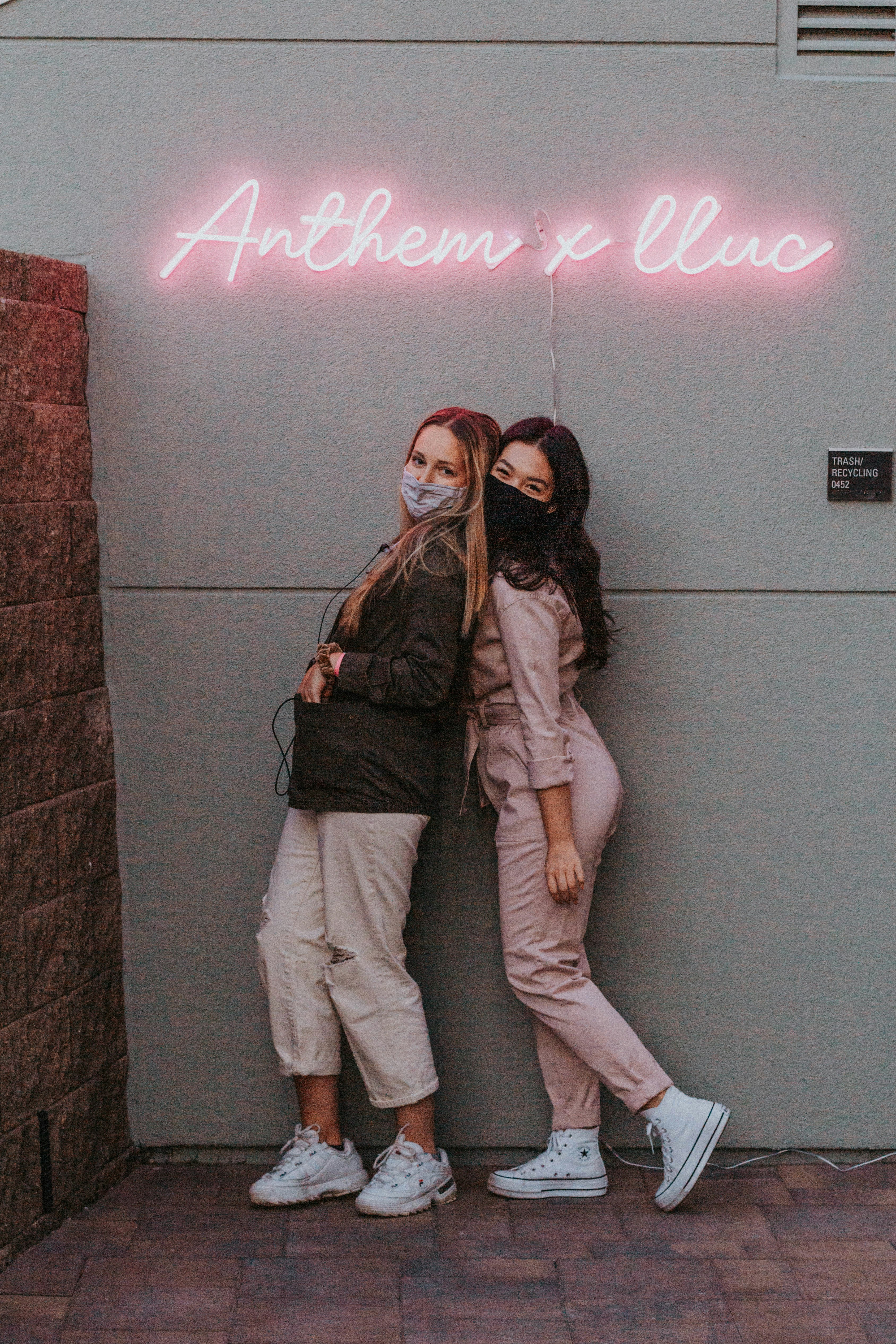 woman in gray jacket and white pants standing beside wall