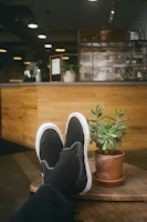 Trendy slip-on shoes placed on a cozy cafe table next to a cup of coffee