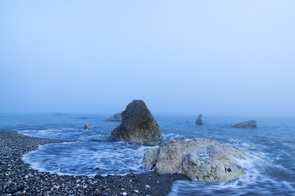 formação rochosa cinzenta no mar durante o dia